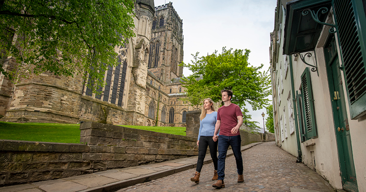 man and woman walking past Durham Cathedral